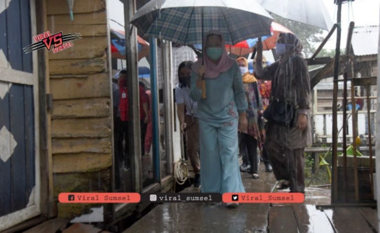 Feby Deru ketua TP PKK Sumsel nekat terobosan hujan demi berikan bantuan paket sembako bagi warga. FOTO :VIRALSUMSEL.COM