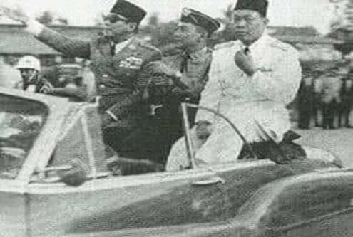 Presiden Soekarno didamping Gubernur Bastari dan Kolonel Harun Sohar dielu-elukan masyarakat Palembang sepanjang jalan menuju lokasi rapat raksasa di halaman kantor gubernuran, 10 April 1962